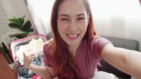 encantador blogger grabando video selfie mientras empaca una maleta para un viaje de viaje