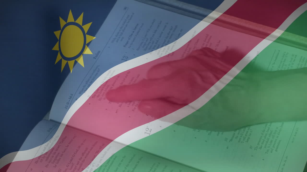 Hand pointing at text in open book with Namibia flag animation overlay