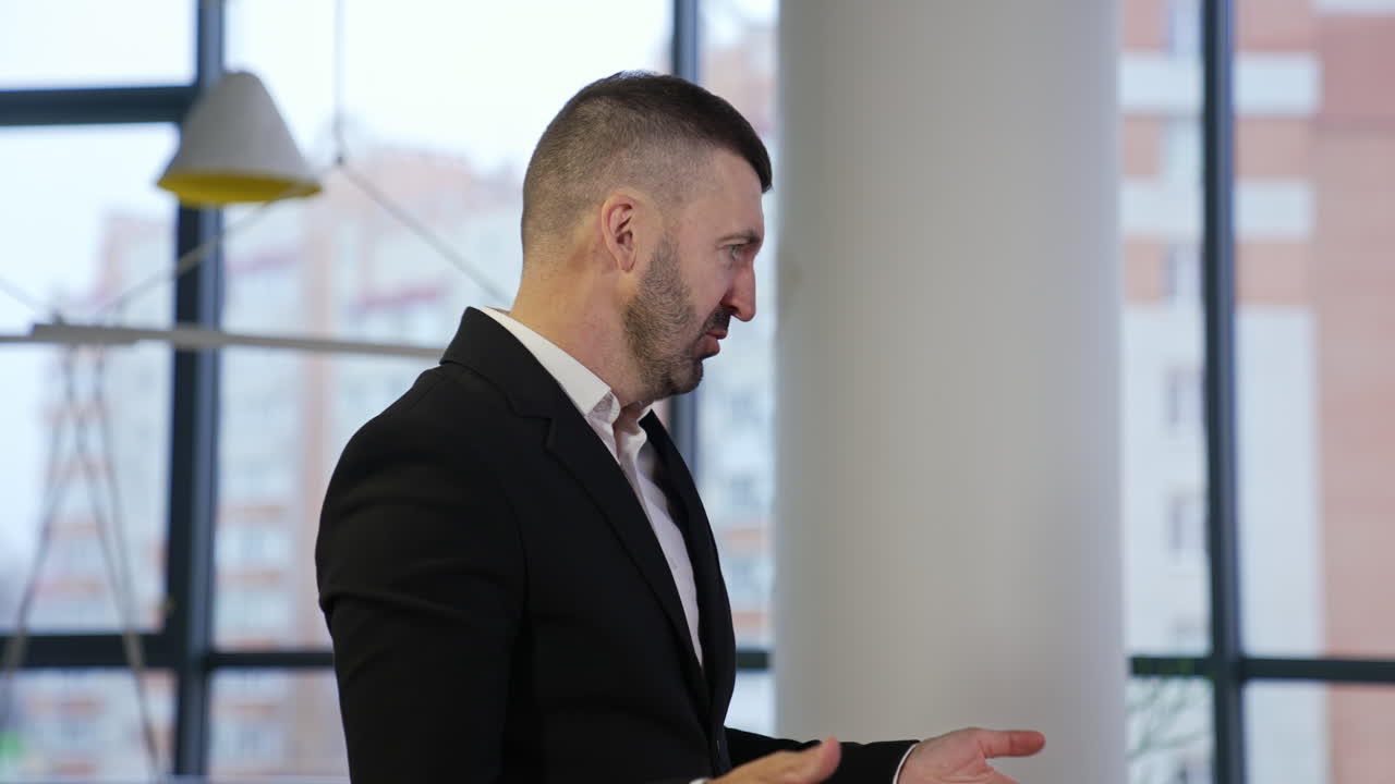 Boss standing with his side and telling something to colleagues. Male in suit explaining work points and gesturing with his hands. Man in a big office.