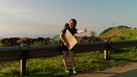 female-hitchhiker-along-the-roadside-with-a-sign-made-from-cardboard-saying-heaven