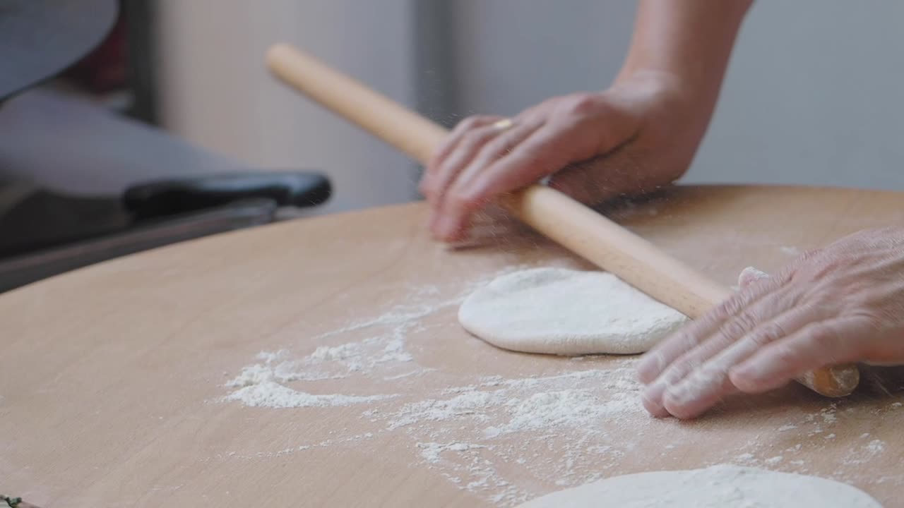 Hands Rolling Dough on a Wooden Surface