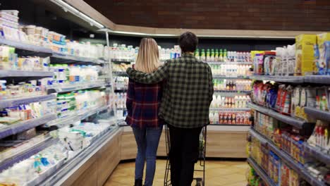 couple pushing shopping cart in supermarket, rare view