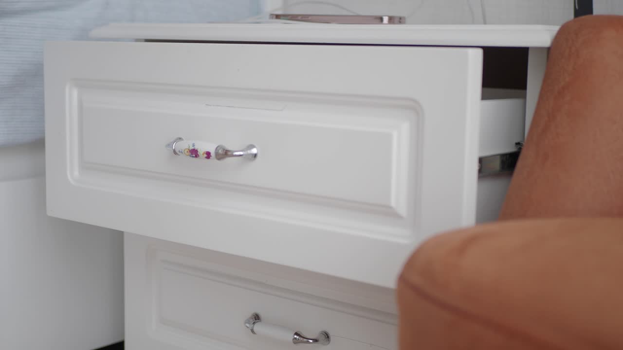 mesita de noche blanca con cajón abierto