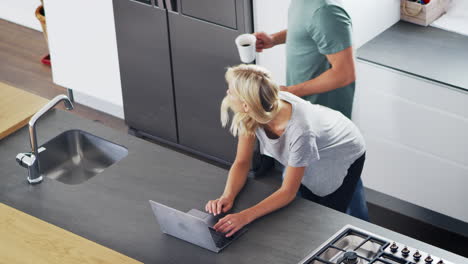 Vista-Aérea-De-Una-Pareja-Mirando-Una-Computadora-Portátil-En-Una-Cocina-Moderna