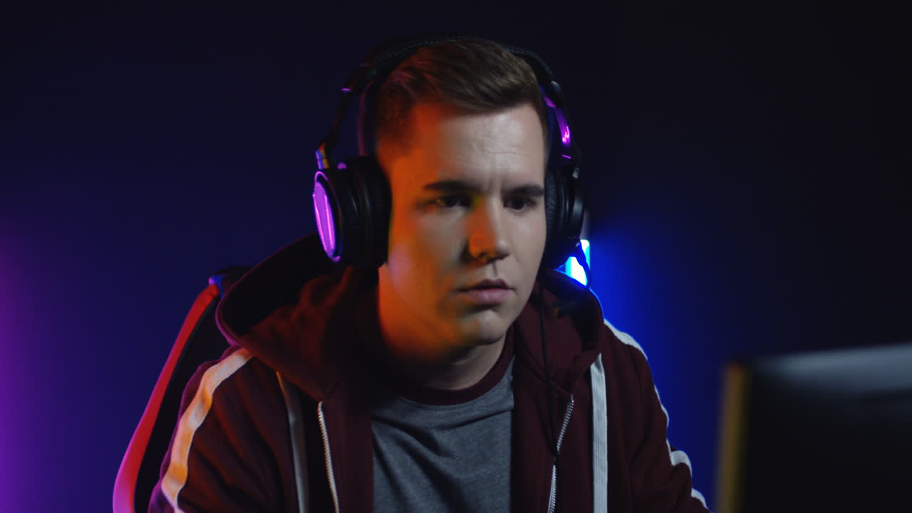 vista de cerca del joven con auriculares y jugando un juego en la computadora y molesto por perder