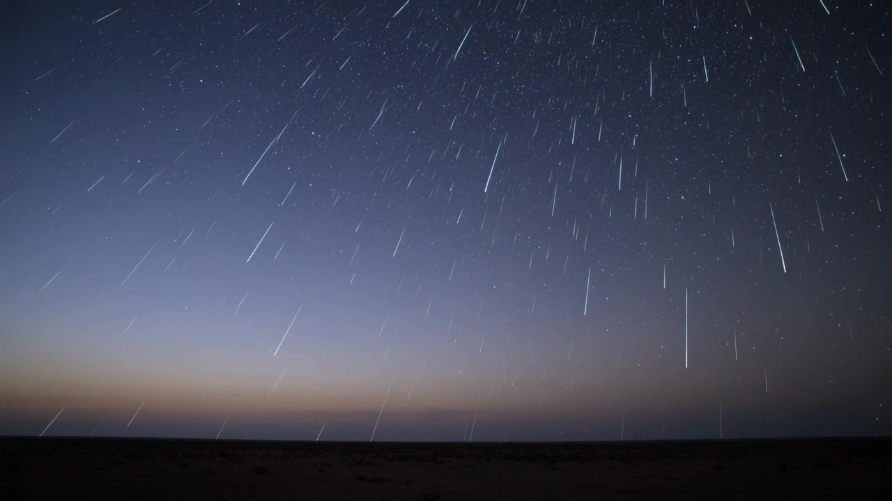 Proudící meteorické pruhy řítící se noční oblohou nad rovinou, jak meteoroidy vstupují do atmosféry