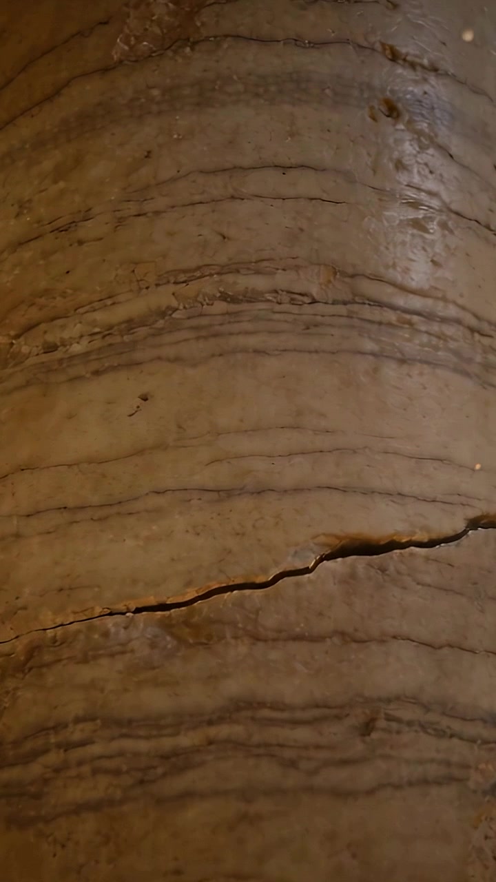 Vertical video: Filming mobile cam moving capturing tan layered surface closeup documenting fissure