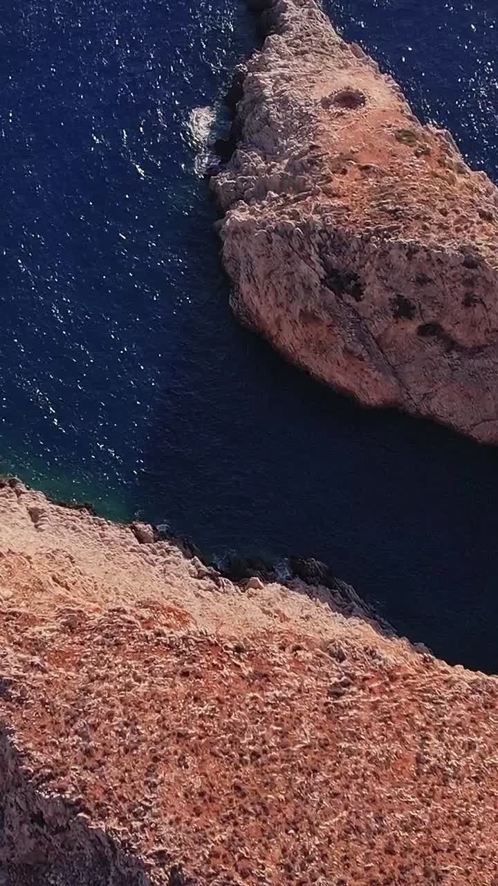 Vista aerea di aspre scogliere rosse e del profondo Mar Mediterraneo blu