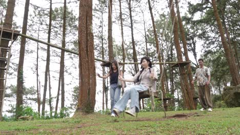 indonesian friends playing on a swing in forest during outdoor travel adventure
