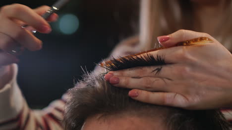 Close-up,-master-hairdresser-does-hairstyle-and-style-with-scissors-and-comb.-Concept-Barbershop.