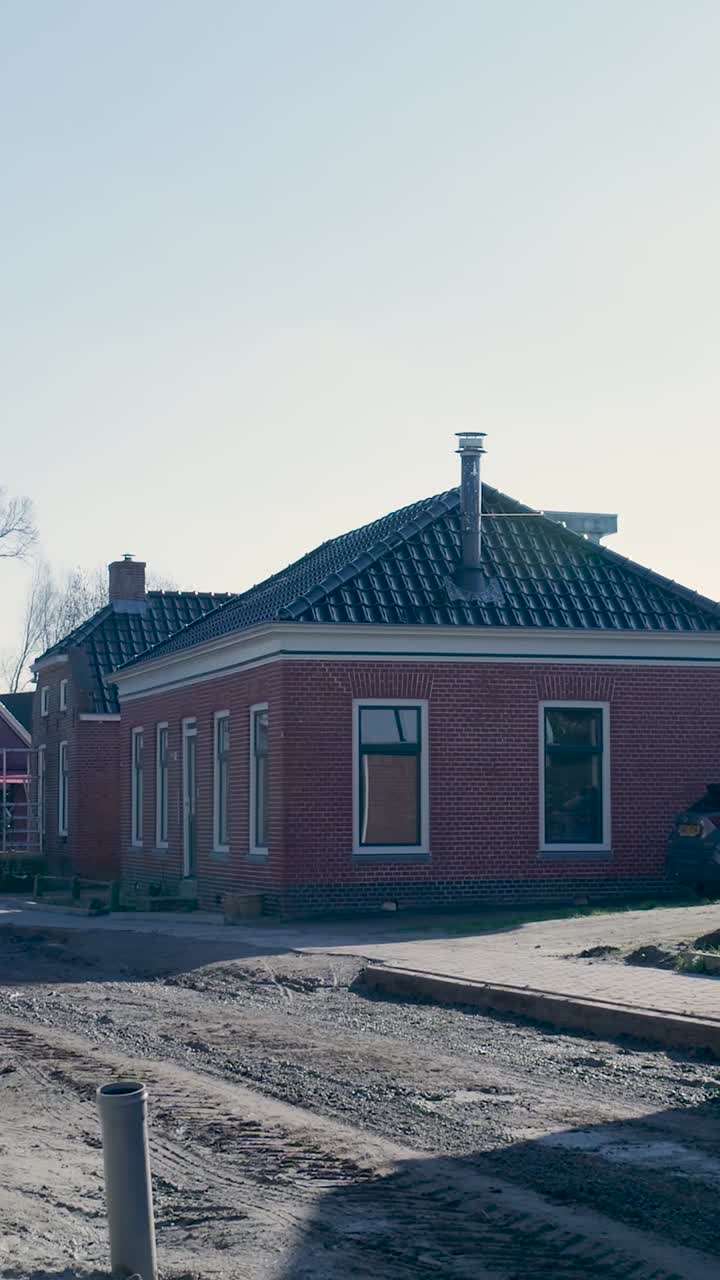 Rött tegelhus bredvid en byggarbetsplats en solig dag