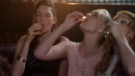 three female friends toasting shot glasses of tequila