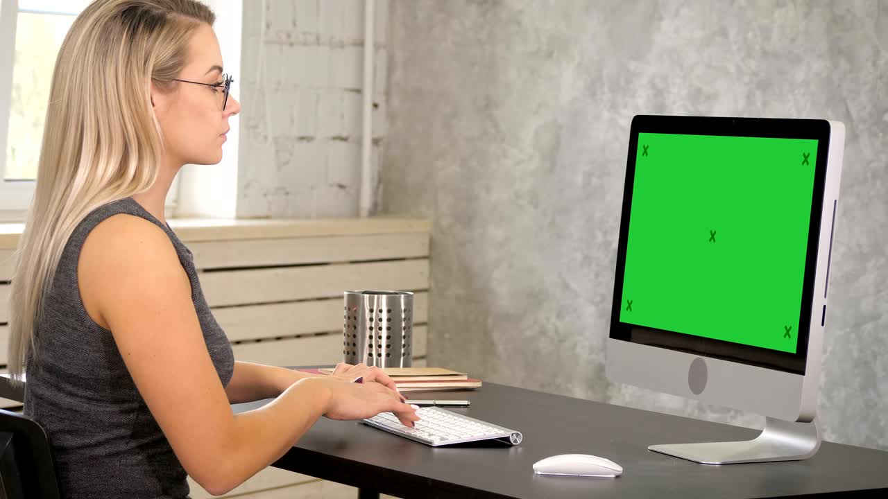 Attractive mature businesswoman working on computer in her workstation. Green Screen Mock-up Display