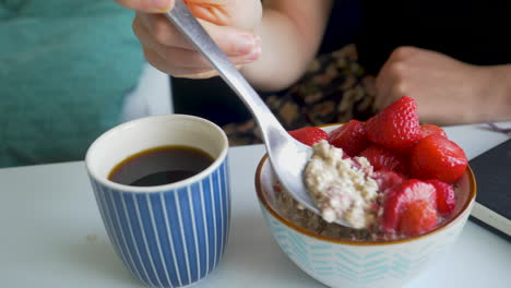 black coffee in a blue mug while eating oatmeal breakfast with a silver spoon.