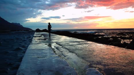 Mujer-Caminando-Por-El-Paseo-Marítimo-De-La-Playa-Durante-El-Anochecer-4k