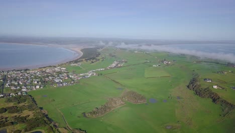 Aerial-flight-over-Stanley-towards-green-fields-and-farms-in-Tasmania,-Australia