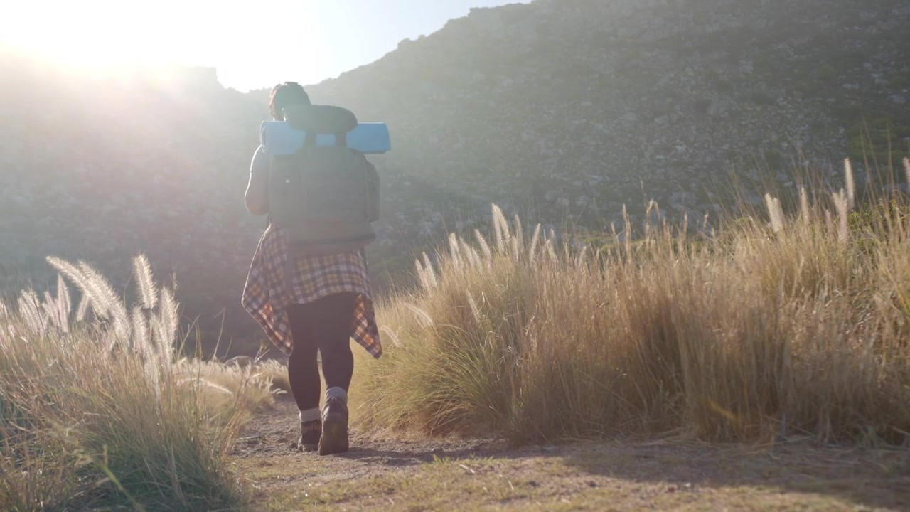 Camera starting low on boots, woman walking toward ridge while technology UI shifting over pack