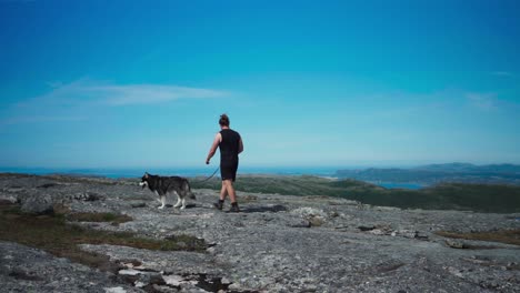 person trekking on a rough terrain with his alaskan malamute dog pet