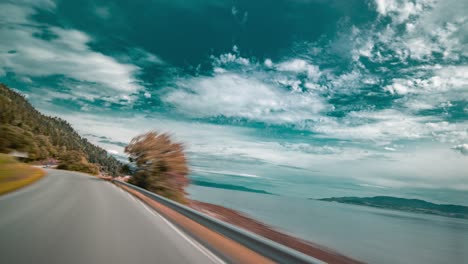 A-drive-on-the-narrow-two-lane-rural-road-along-the-calm-Tingvollfjorden-fjord-near-Sunndalsora,-Norway