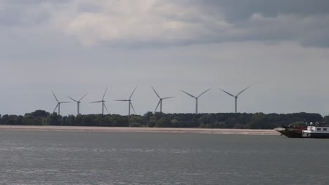 line of turning wind turbines along the waterway