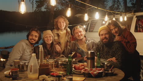 retrato de amigos felices en la cena de campamento por la noche