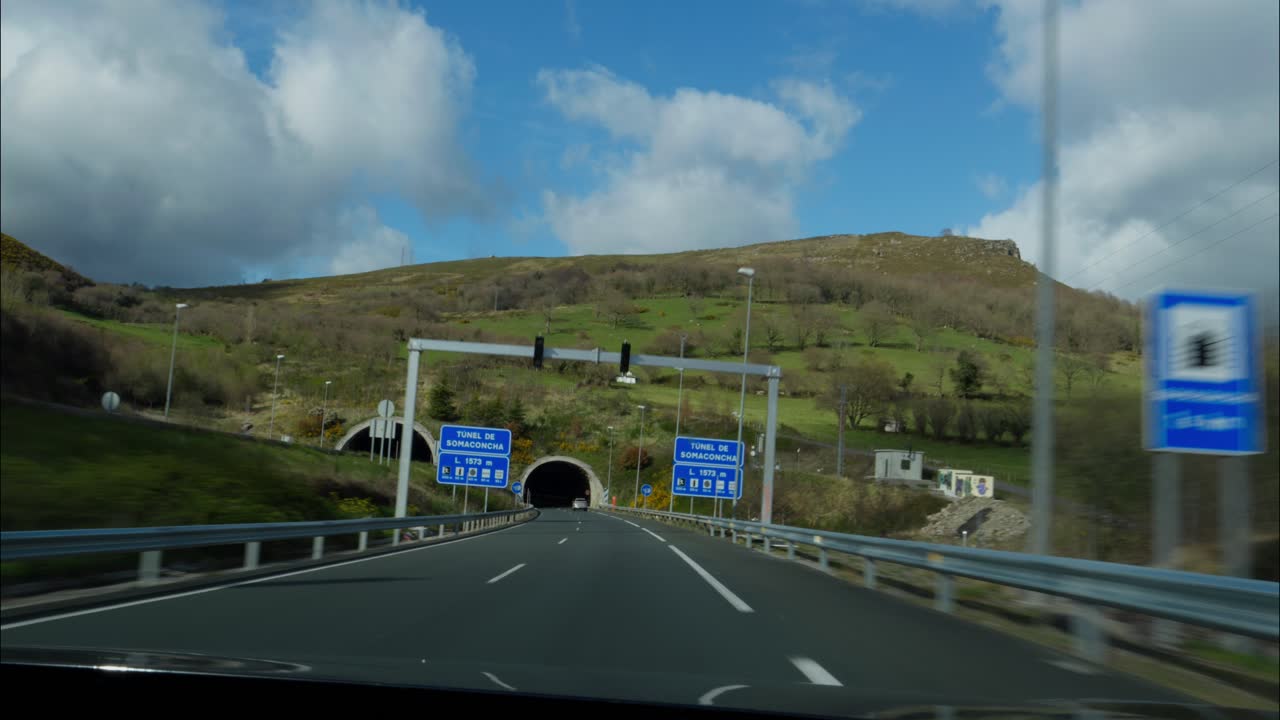 Bil kører på bjergmotorvej og kører ind i en tunnel