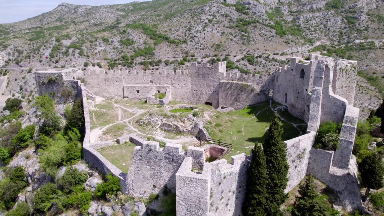 Blagaj Fæstnings stenmure danner en indhegning tværs over et stenet plateau i Bosnien-Hercegovina; luftfoto afslører bag de bageste mure til en åben, ødelagt gårdsplads