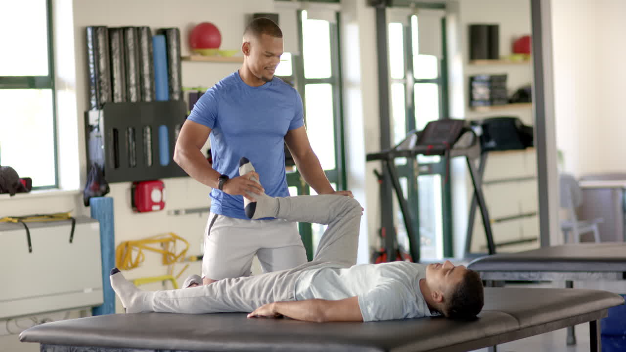Physical therapist stretching patient's leg during rehabilitation session in clinic