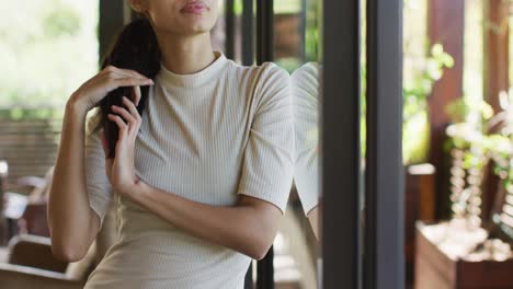 thoughtful biracial woman standing at window and looking outside