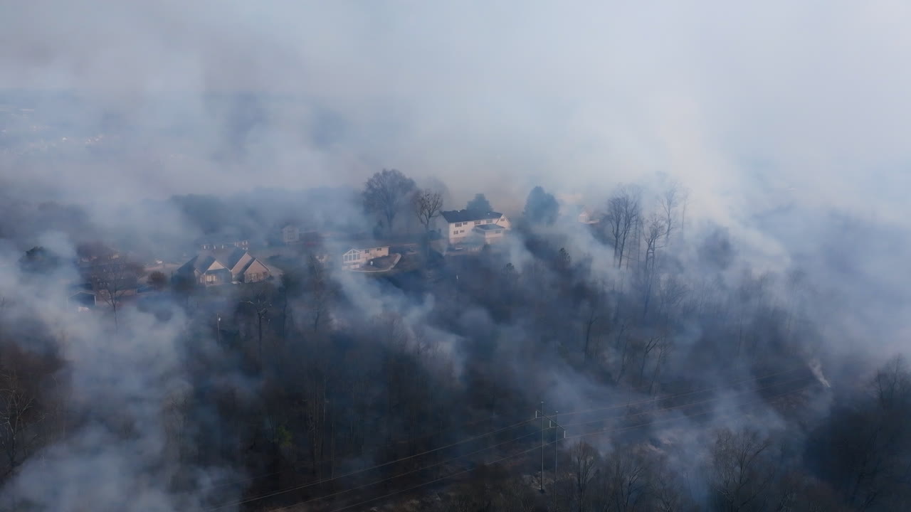 Filmato aereo statico con drone di un incendio boschivo a Rossville, Georgia, con case coperte di fumo sulla cima di un crinale.