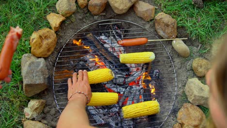 high angle view of friends roasting hot dog and corn on campfire 4k