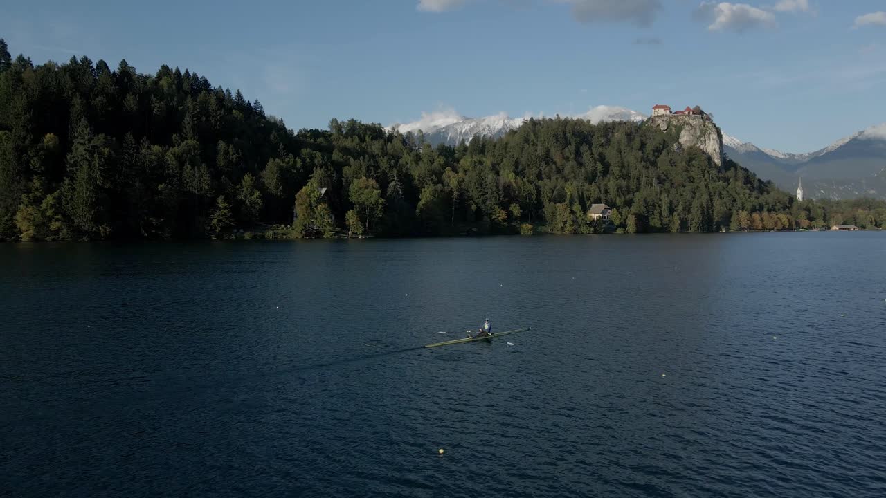 Alpi Giulie come sfondo per i rematori sul Lago di Bled con l'isola della chiesa, Slovenia