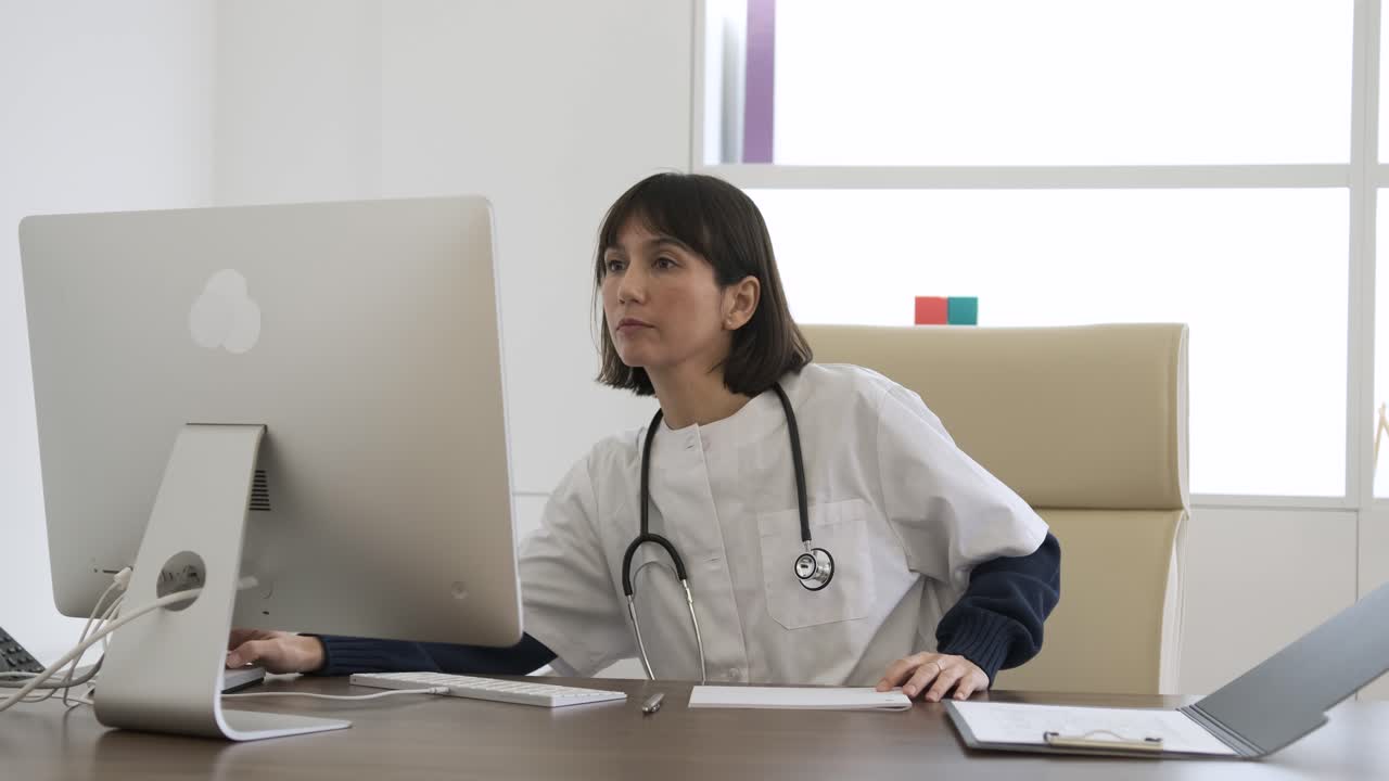 Female doctor writing notes and using computer