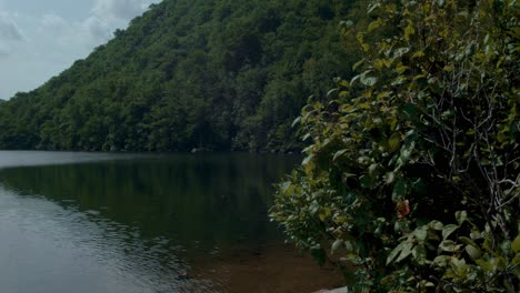 Un-Lago-Tranquilo-Se-Encuentra-Frente-A-Dos-Montañas-Verdes-Mientras-La-Cámara-Gira