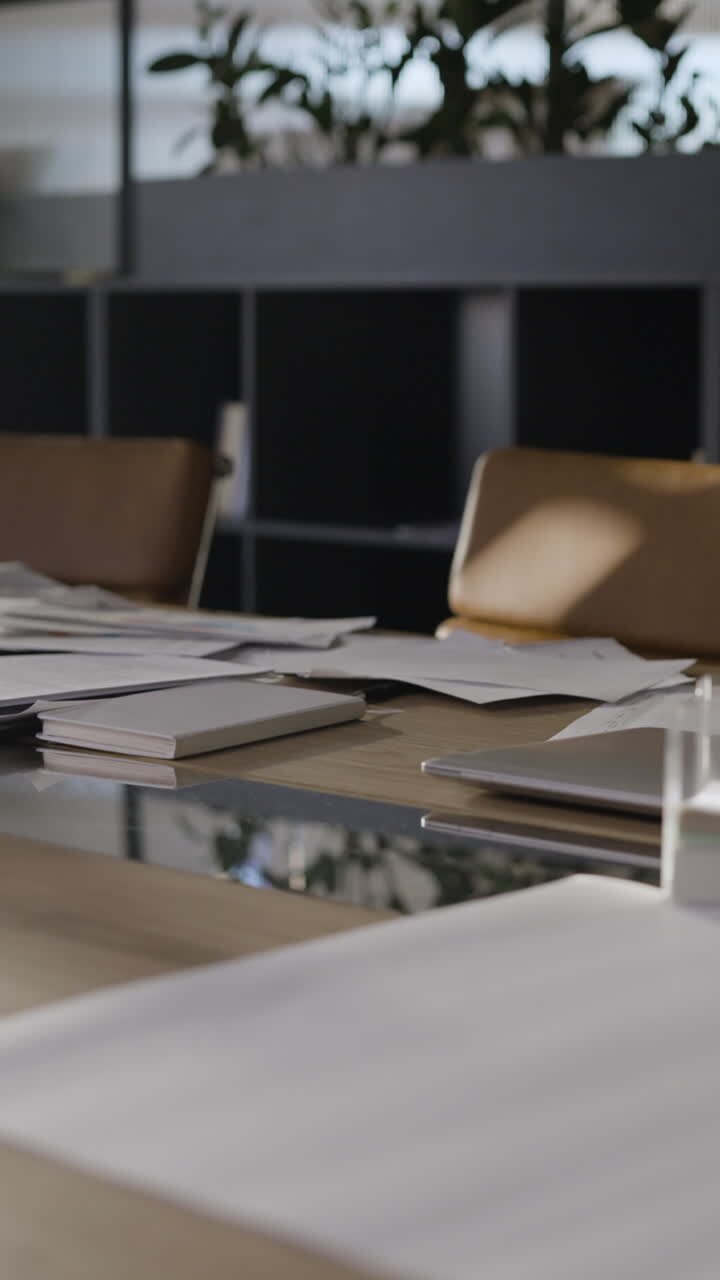 sala de reuniones ocupada con papeles y computadoras portátiles