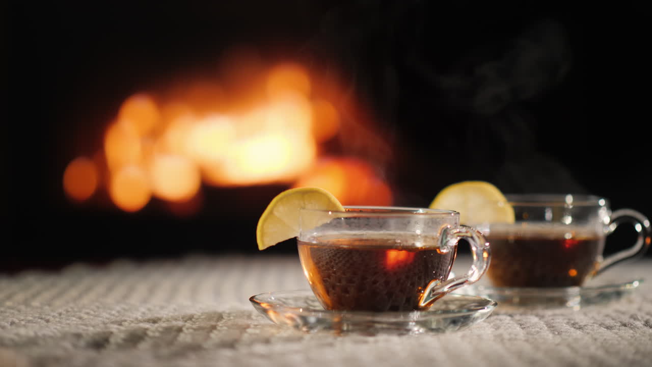 벽난로 옆 테이블에 있는 뜨거운 두 컵 증기는 뜨거운 음료에서 나옵니다