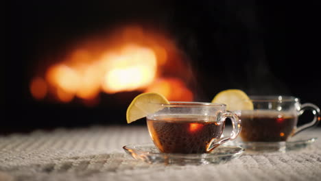 dos tazas de flujo caliente sobre una mesa junto a la chimenea el vapor proviene de una bebida caliente