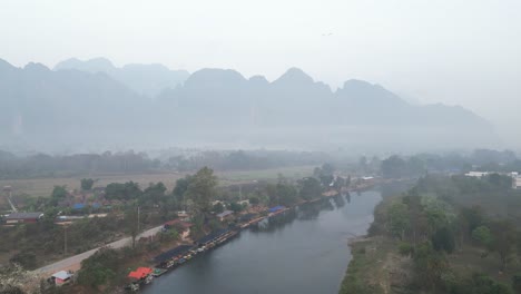 drone aerial shot of misty mountains and river in vang vieng, the adventure capital of laos