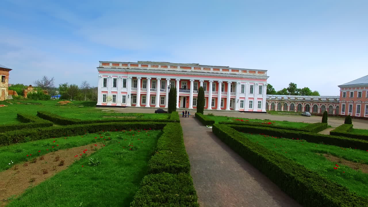 Lawn and flower-beds in front of the beautiful palace with columns. Neighboring buildings of a museum are at reconstruction.