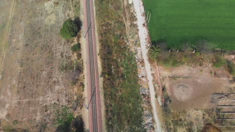 Long-straight-railway-track-crossing-between-the-green-fields-in-Punjab