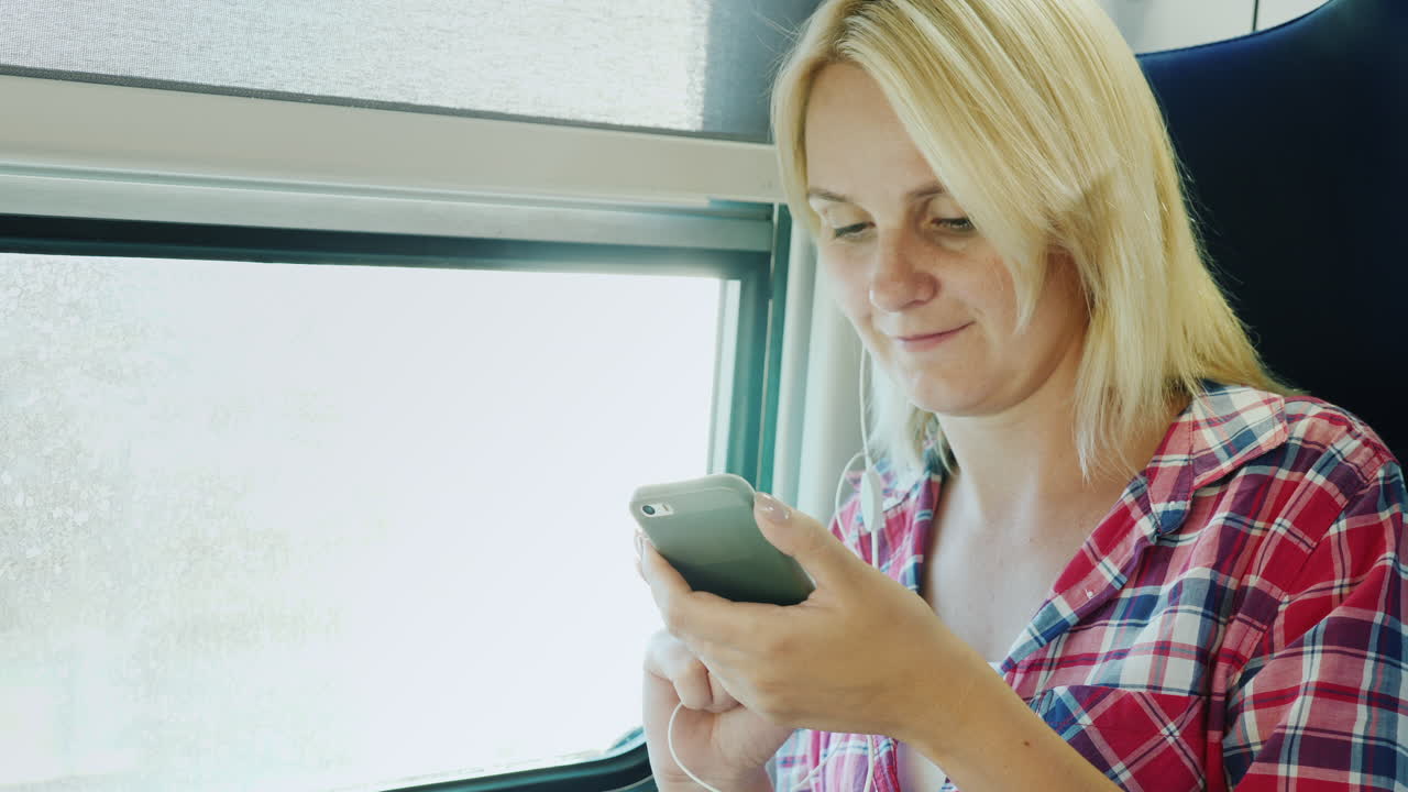 Una giovane donna viaggia al secondo piano di un treno ed è seduta accanto al finestrino.