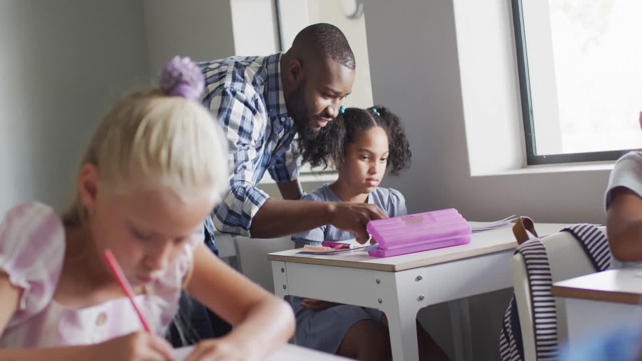 video de un feliz maestro afroamericano ayudando a una chica biracial durante las lecciones