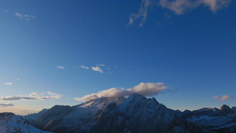 aerial footage that starts in the sky and pans down to reveal a mountain range in the dolomites bathed in the light of sunrise.