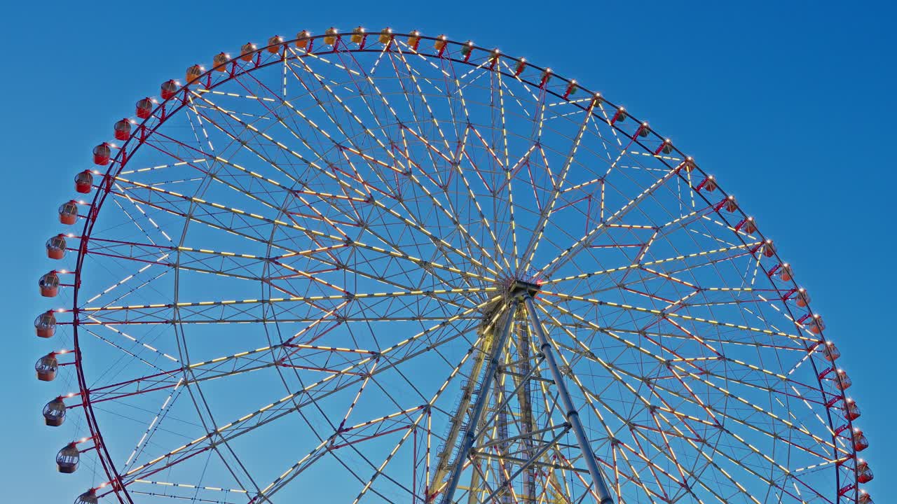 A close-up shot of the Diamond and Flower Ferris Wheel in Tokyo on a sunny day with a vibrant blue sky