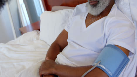 médico comprobando la presión arterial de un hombre negro maduro en un hogar cómodo 4k