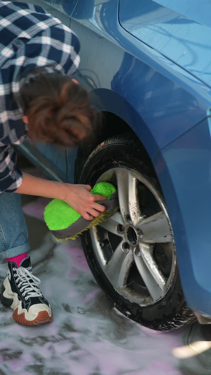mujer lavando la rueda de un coche