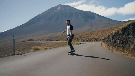 man skateboarding downhill on a scenic mountain road