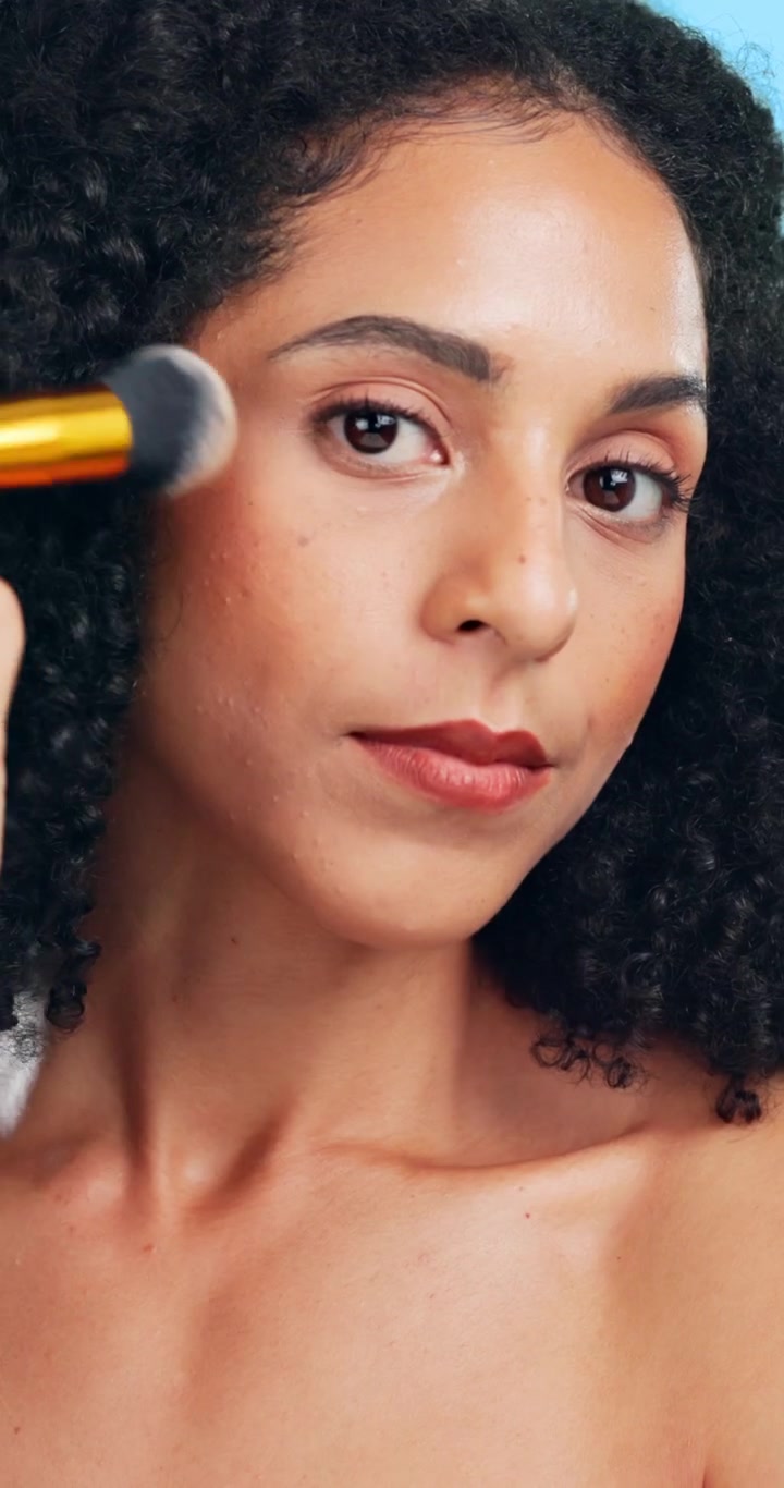Giovane donna che applica il trucco sul viso con un pennello
