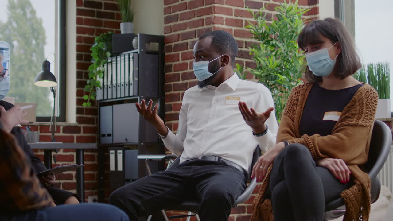African american man talking to group of people at aa therapy meeting about addiction