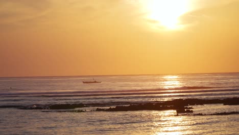 A-small-boat-moves-up-the-coast-with-the-sun-hanging-low-in-the-background,-filmed-in-UHD-4K